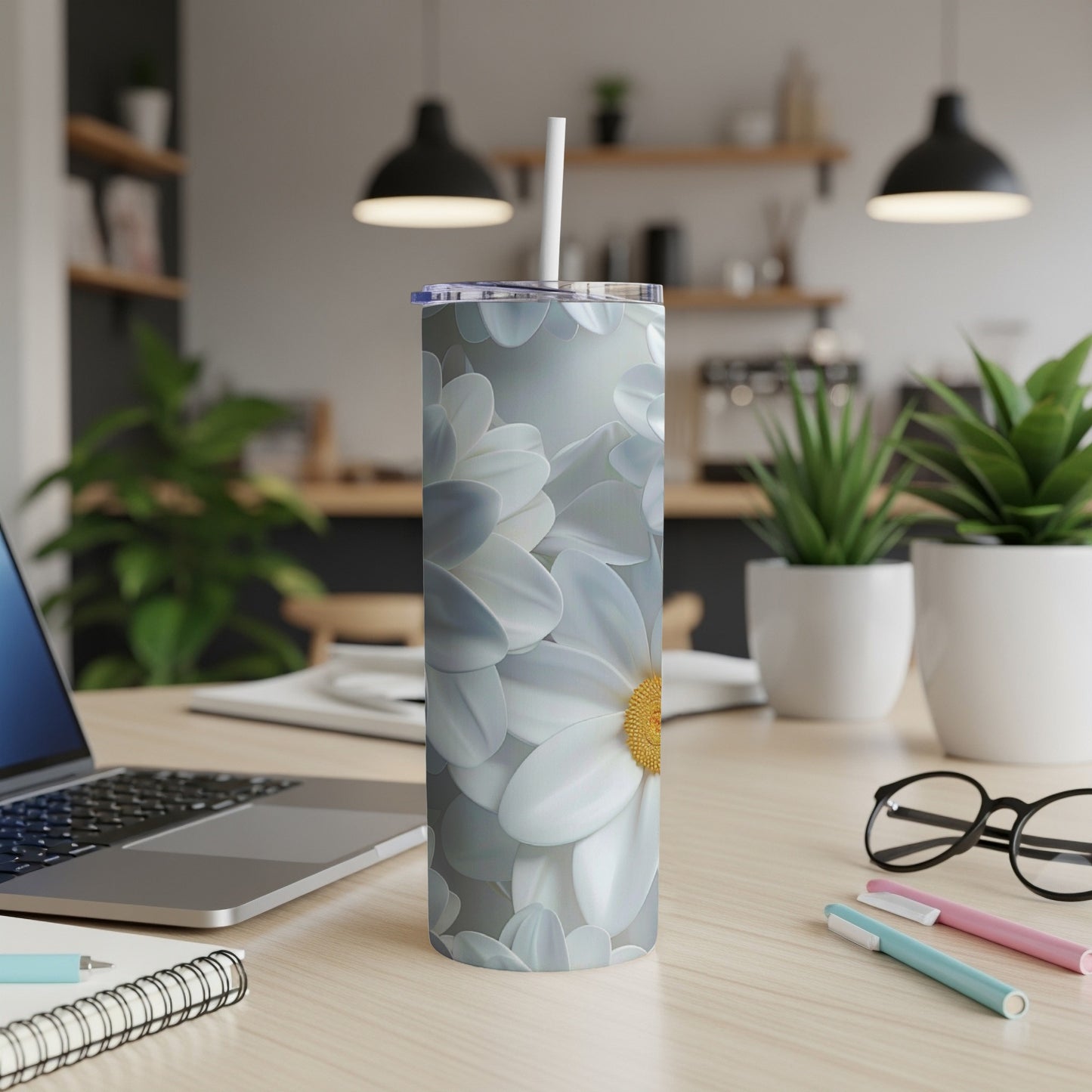 White and yellow daisy pattern on a silver tumbler with a straw.