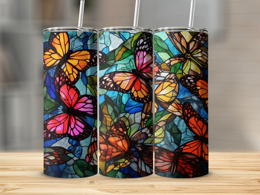 Three stained-glass tumblers with colorful butterfly designs and straws.