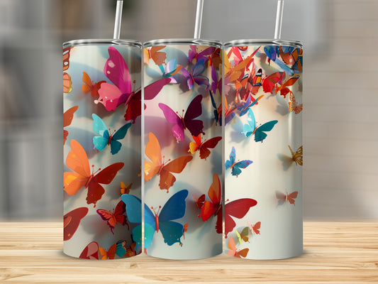 Three tumblers with colorful butterfly designs sit on a wooden surface.