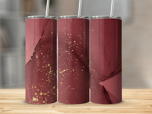 Maroon tumbler with gold glitter accents on a wooden surface.