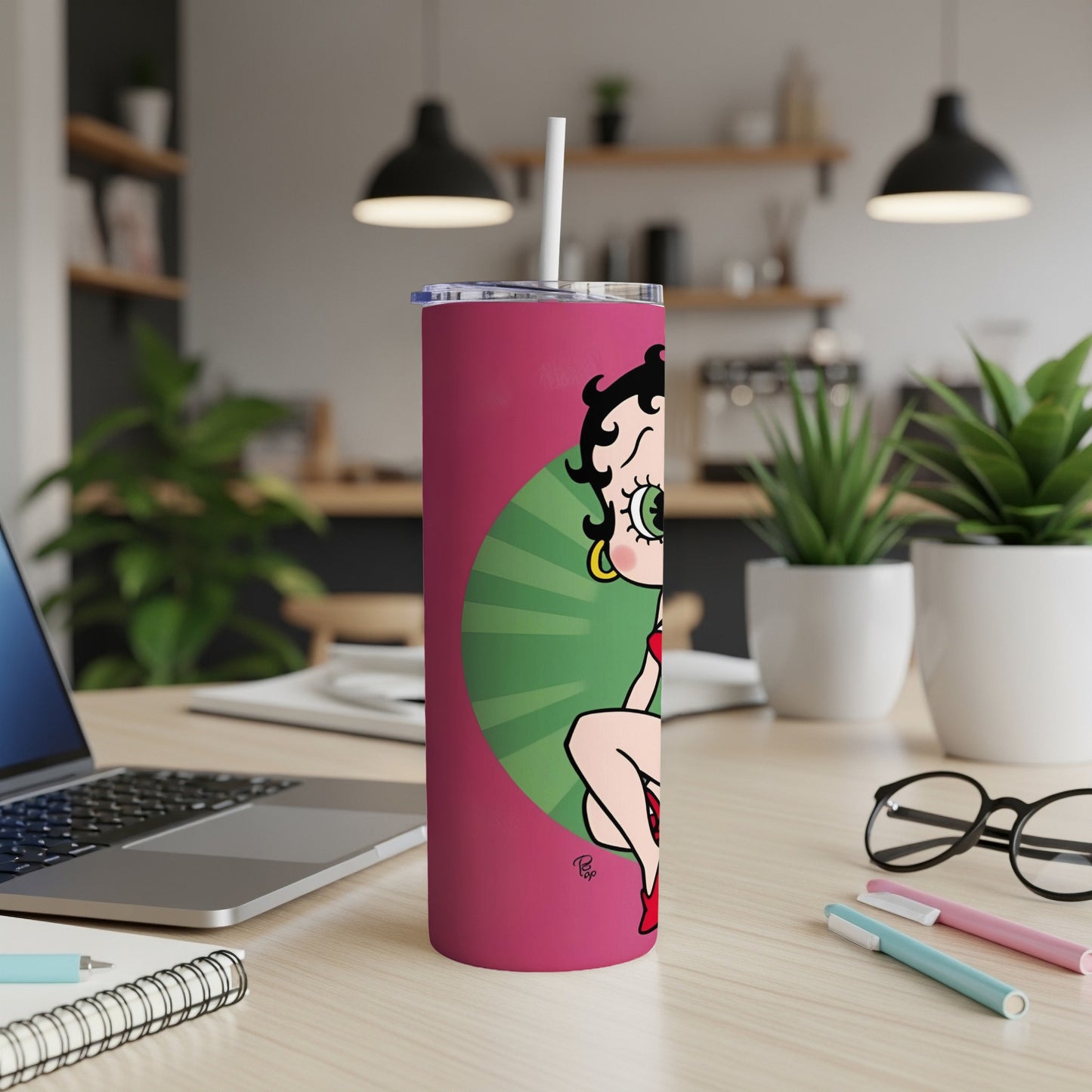 Betty Boop on a pink tumbler with straw, on a desk.