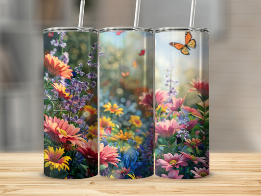 Three tumblers with vibrant floral designs and butterflies against a blurred garden background.