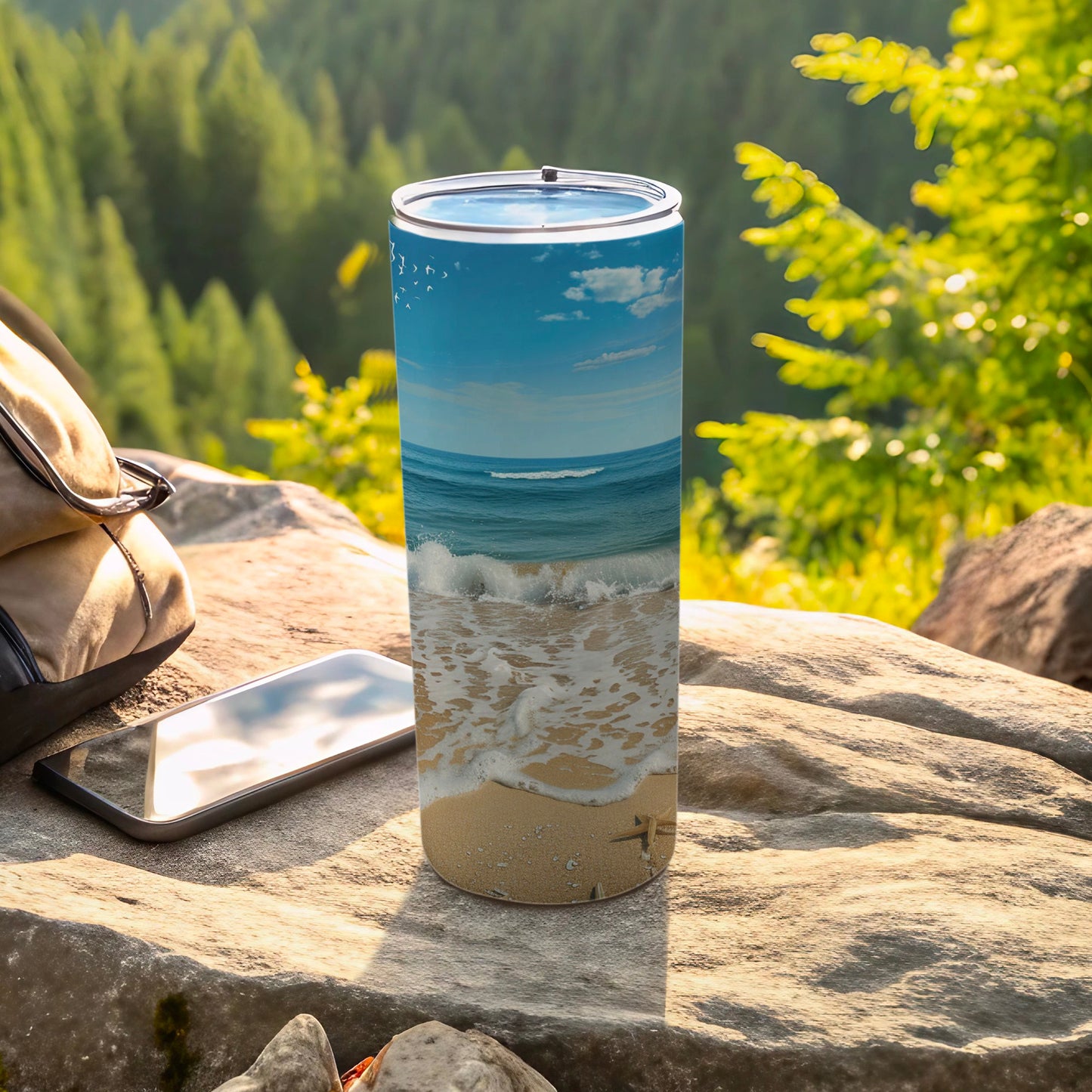 Beach scene tumbler with waves, sand, and starfish on rocky surface with phone.