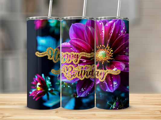 Floral happy birthday tumbler with glitter text on a wooden surface.