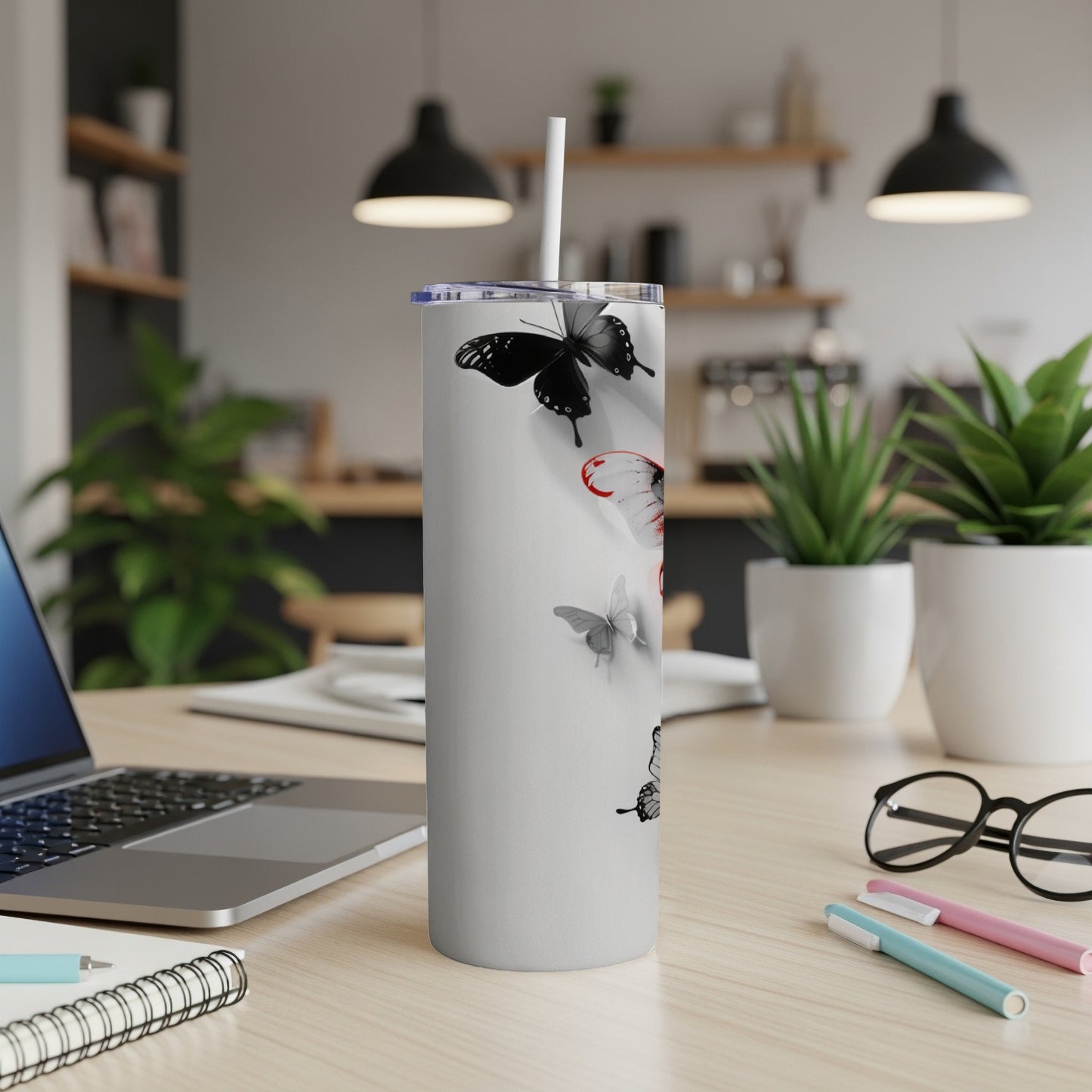White tumbler with black and red butterflies on a desk.