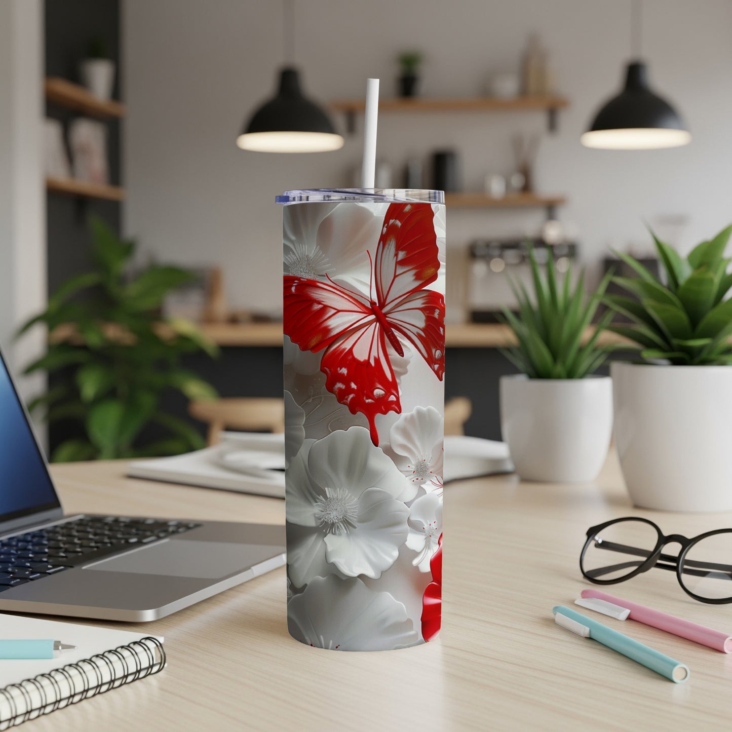 White tumbler with red butterfly and floral design on a desk.