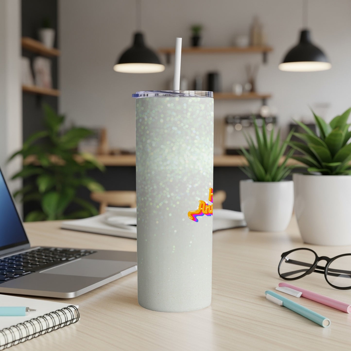 Sparkling white tumbler with "Angel" text, resting on a desk with a laptop.