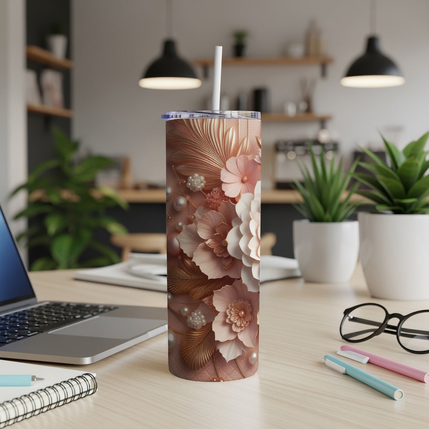 Rose gold floral tumbler with white straw on a desk with a laptop.