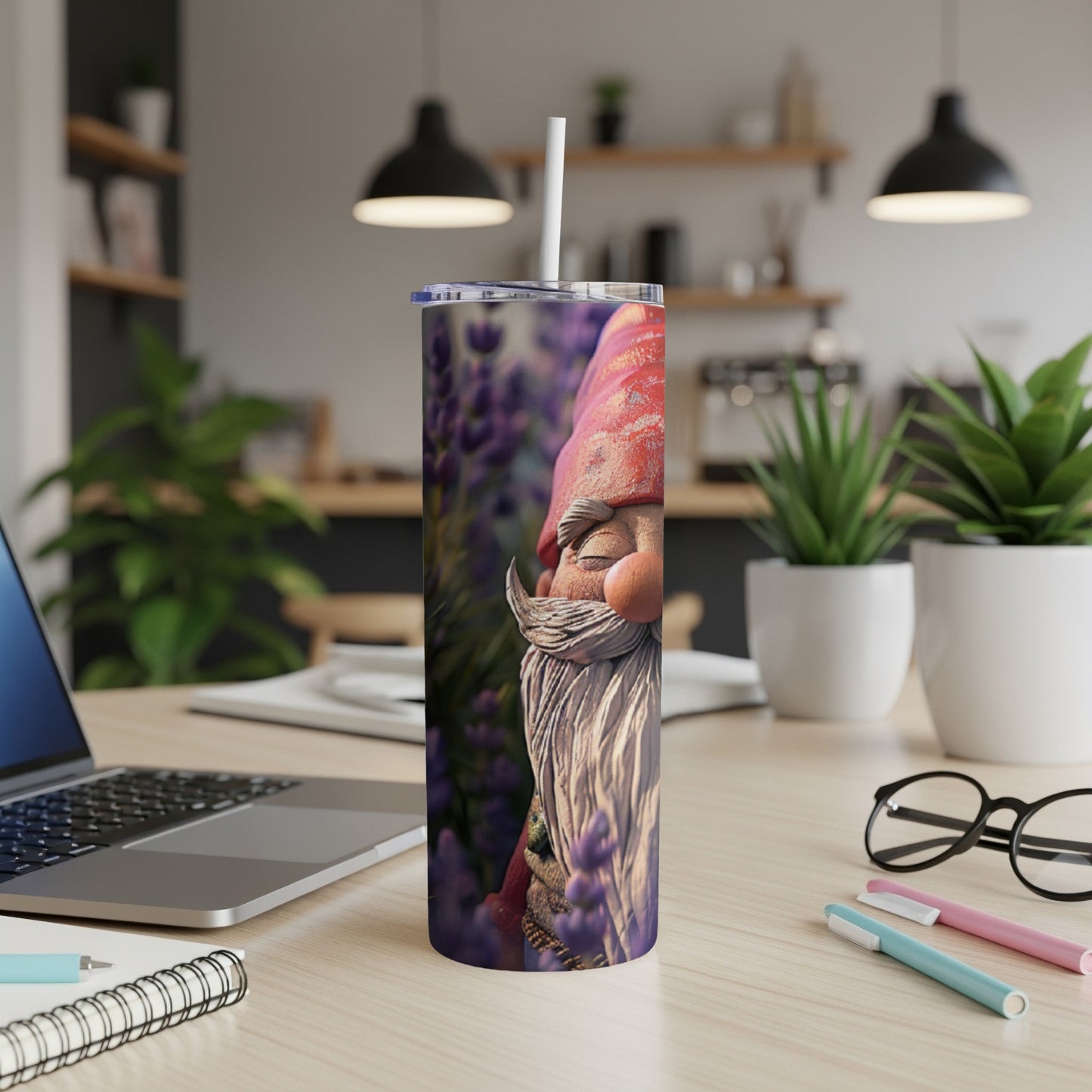 Tumbler with gnome face and lavender flowers on a desk.