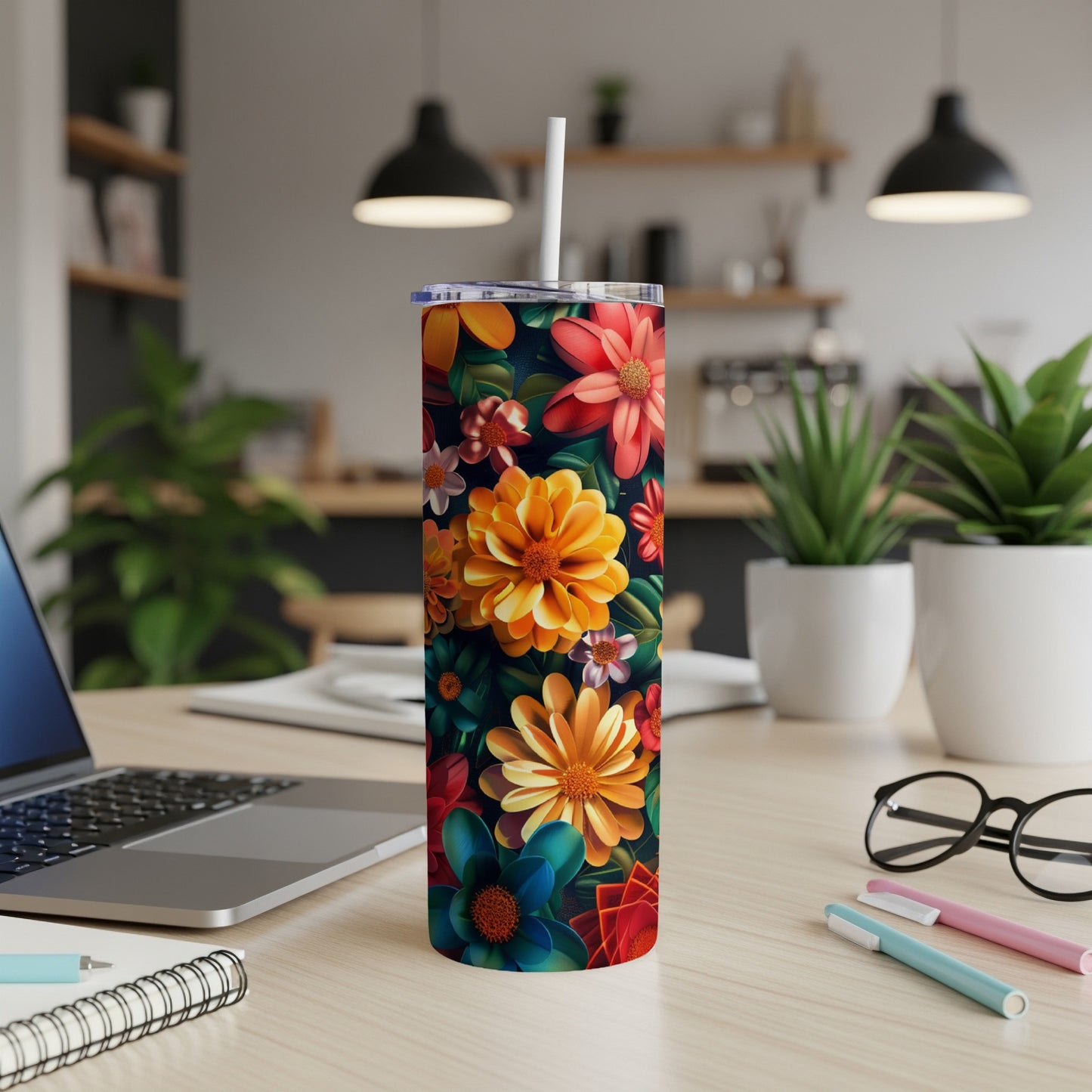 Tall tumbler with vibrant floral pattern and straw on a desk.