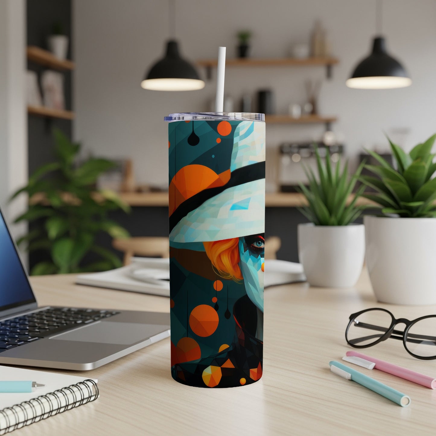 Tumbler with abstract portrait and geometric design, set on a desk.
