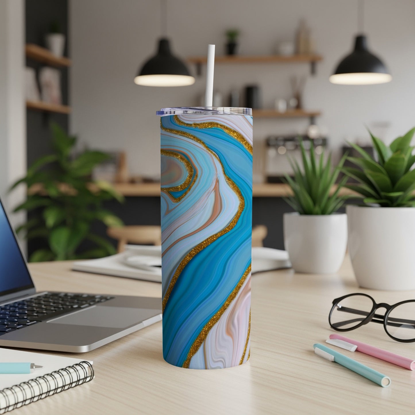Blue and gold marbled tumbler with white straw on a desk.