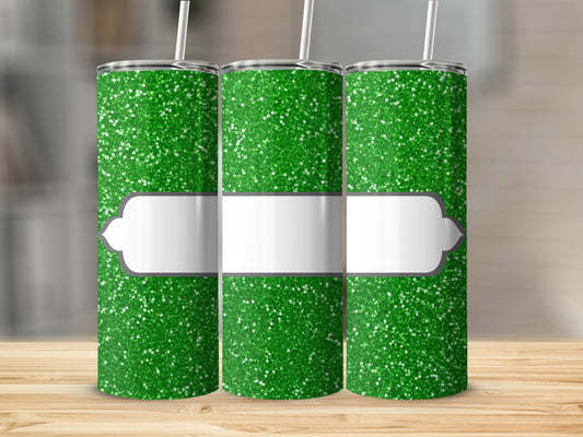 Three green glitter tumblers with white label and straws on a wooden surface.