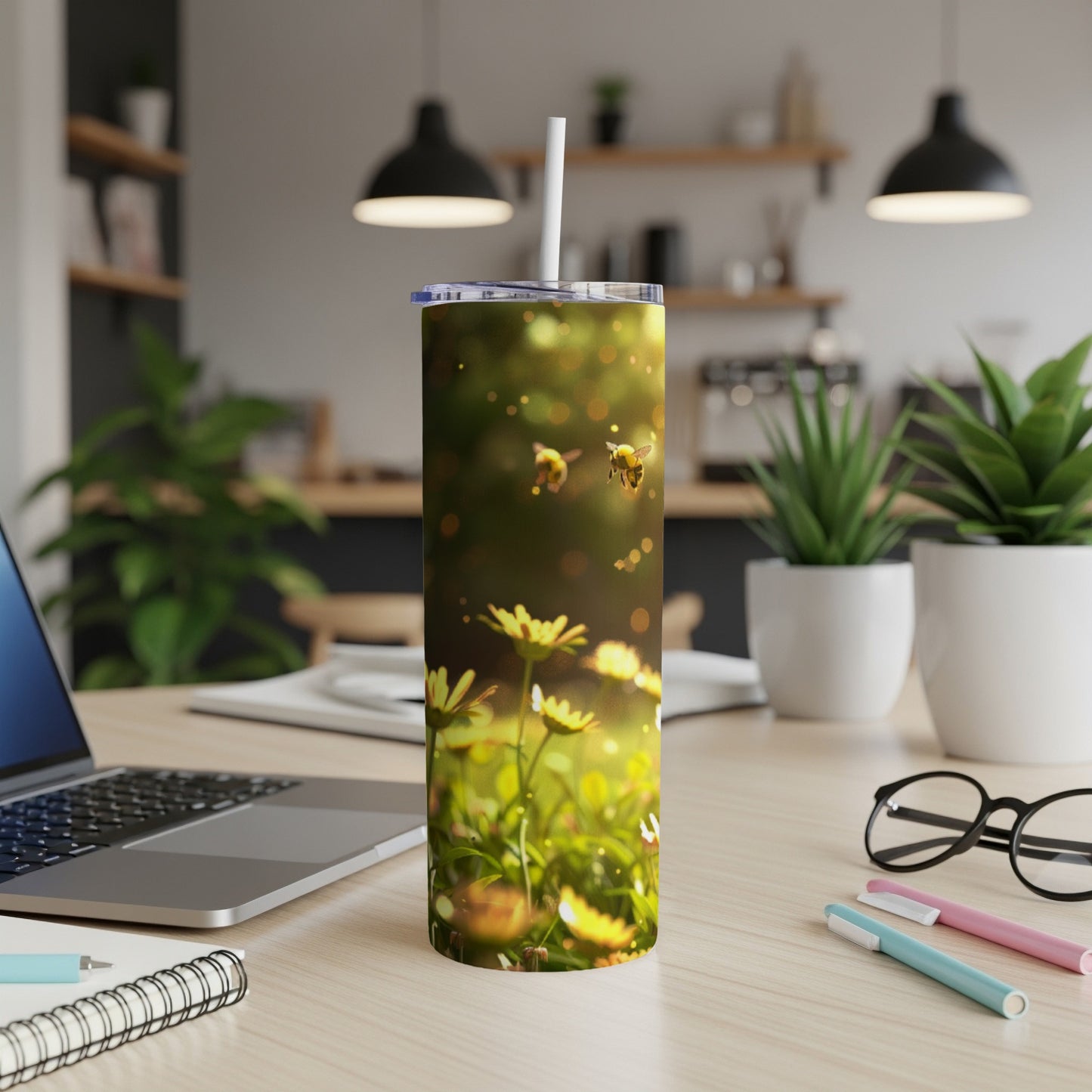 Two bees fly amongst yellow flowers on a tall, slender tumbler.