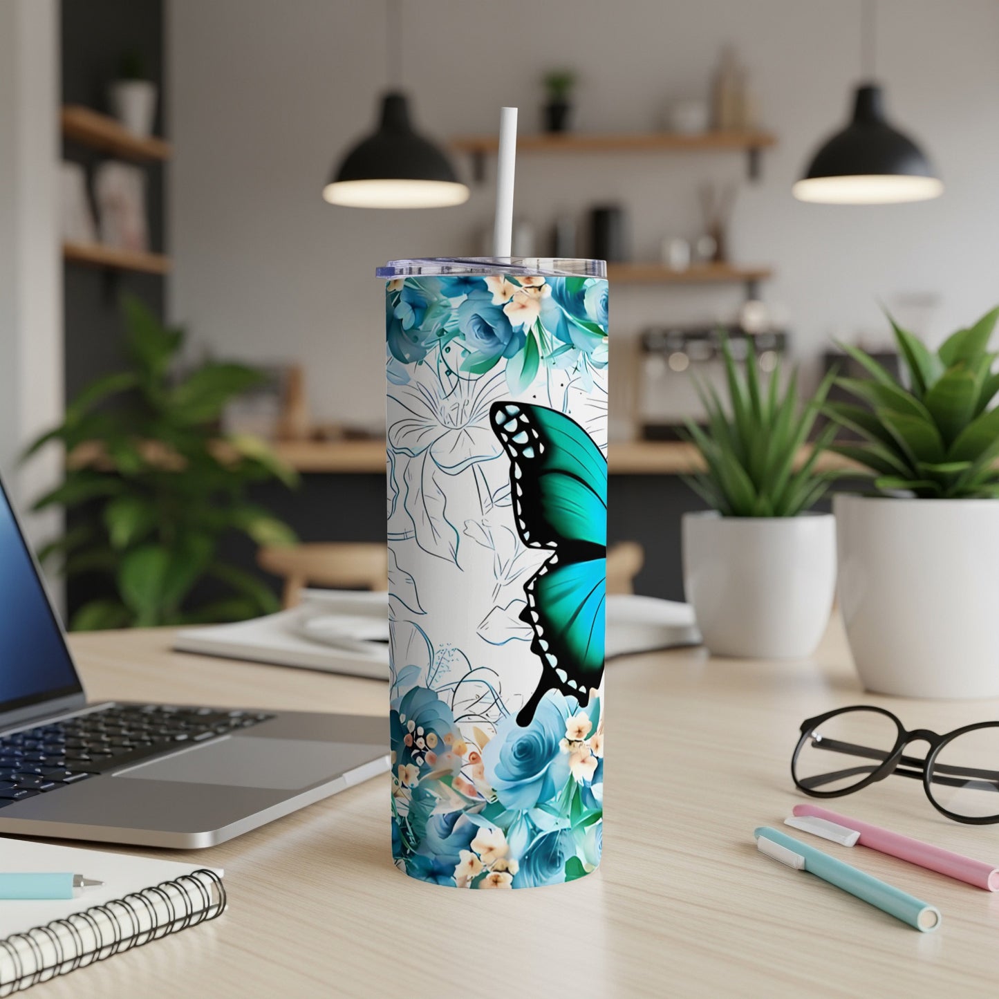 Blue butterfly and floral print skinny tumbler on desk with laptop and pens.