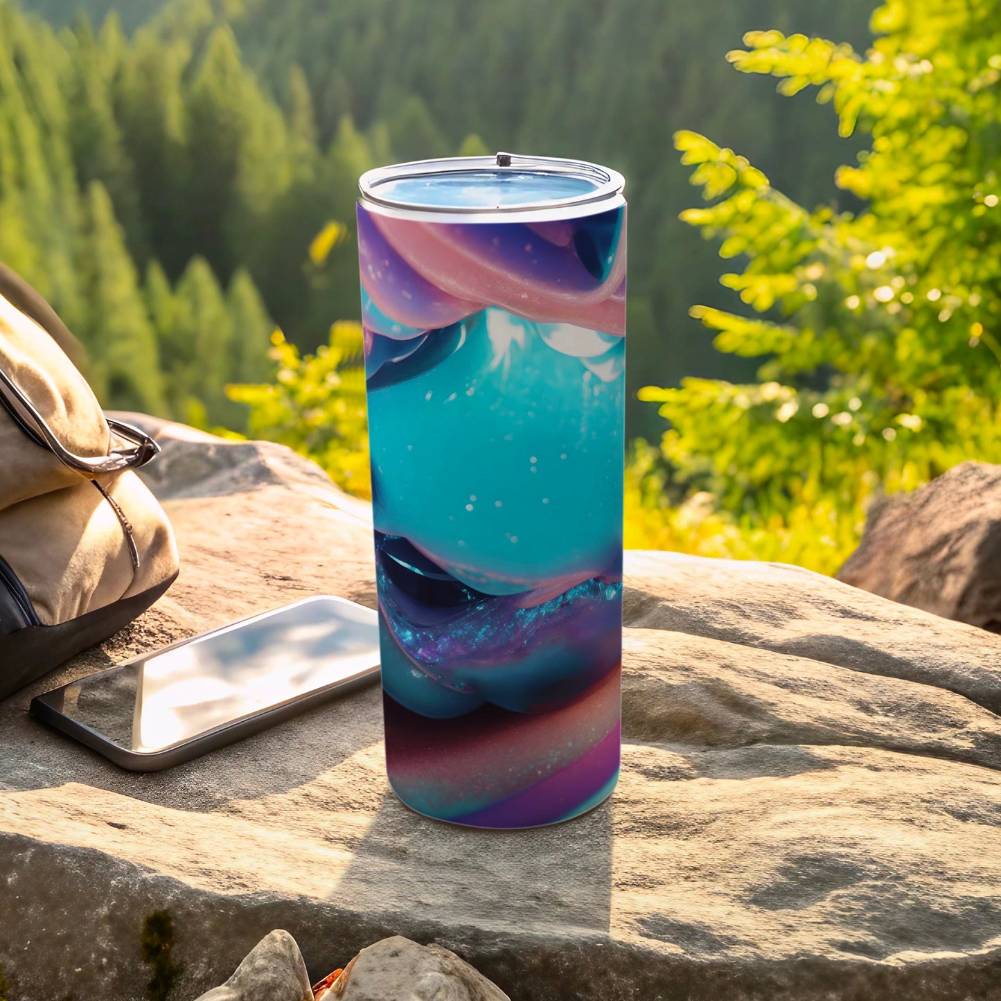 Tall tumbler with abstract blue, pink, and purple swirls on an outdoor rock.