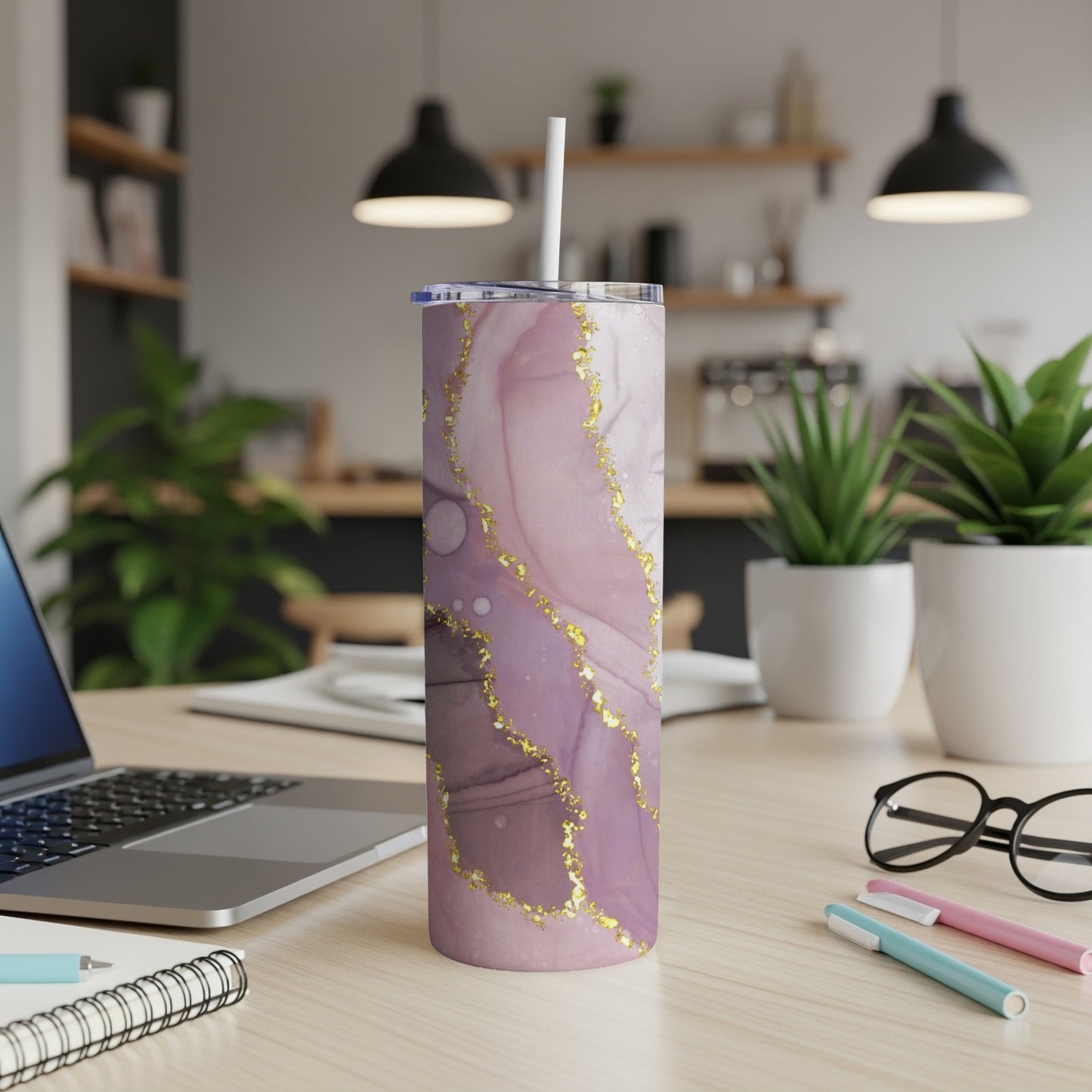 Purple and gold abstract marble pattern tumbler with straw on desk.