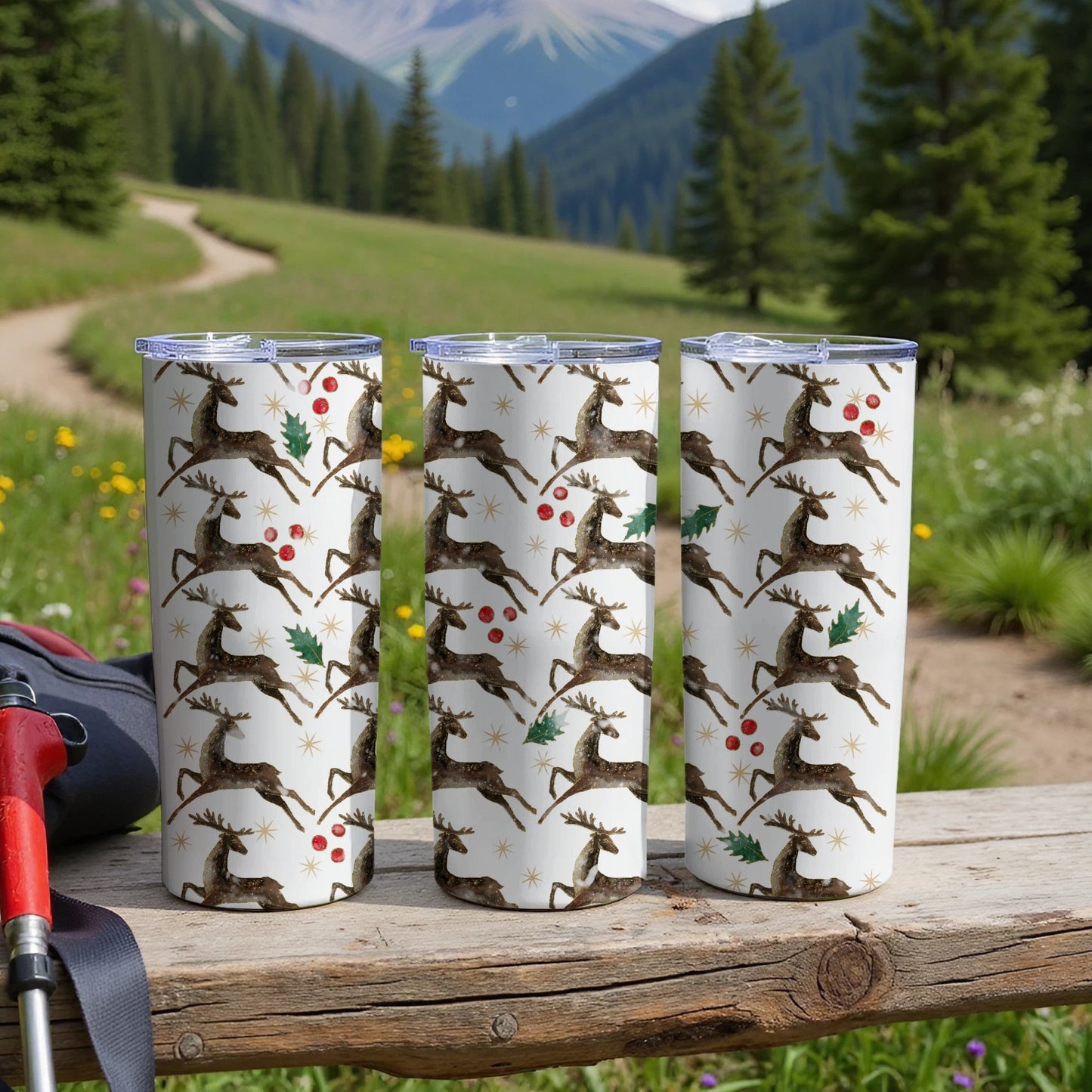 Three tumblers with a deer and holly pattern on a wooden surface.