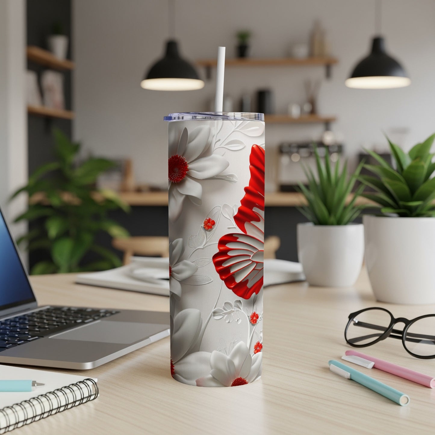 White tumbler with red butterfly and floral design on a wooden desk.