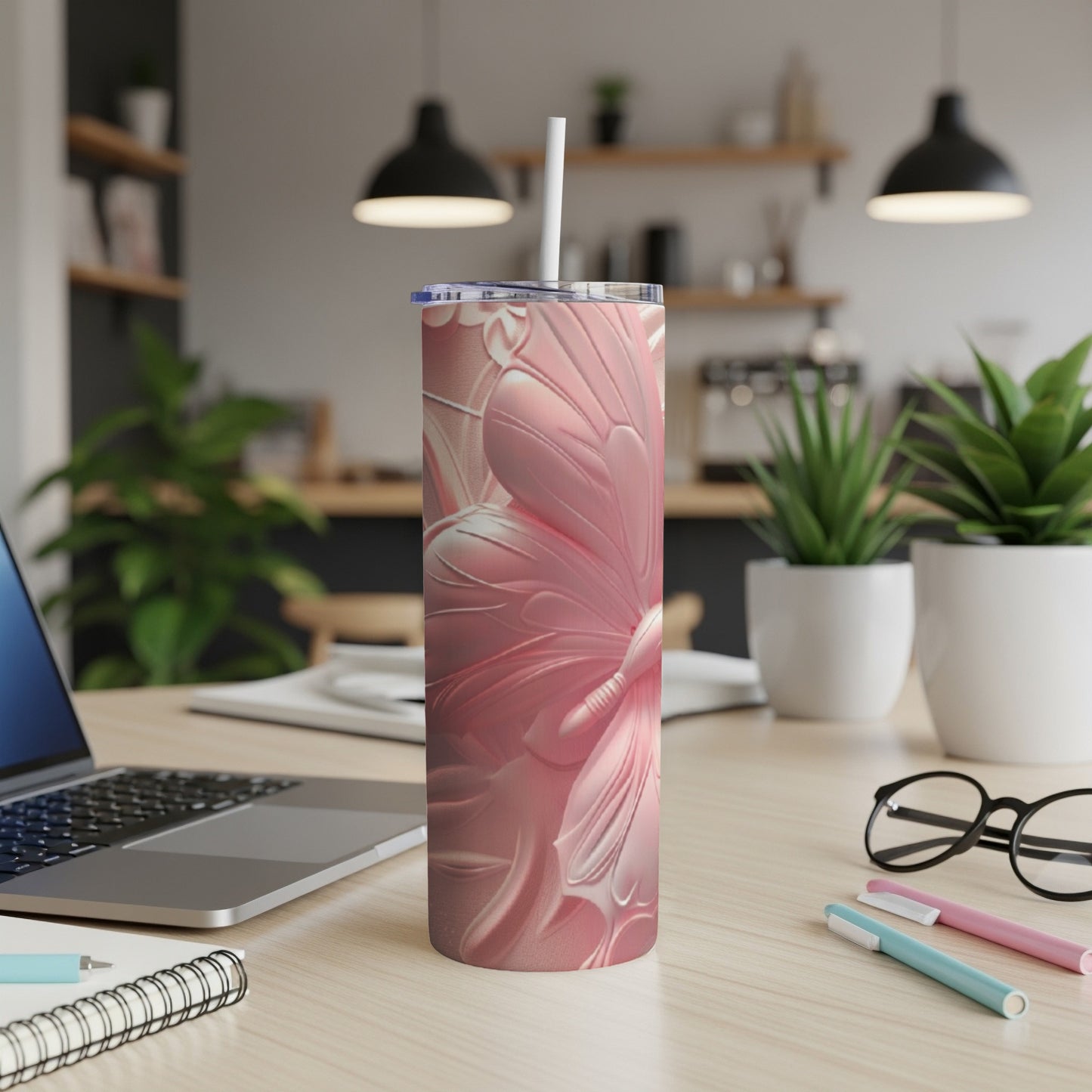 Pink butterfly tumbler with straw on a desk with laptop and pens.