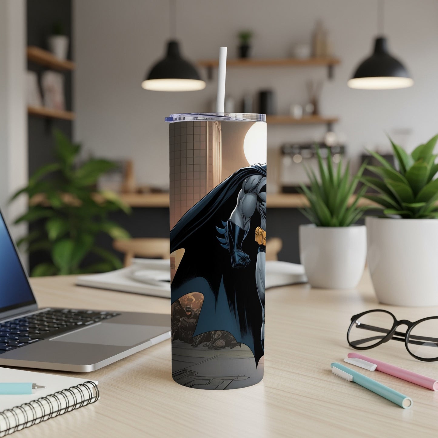 Batman illustration on a white tumbler with a straw, on a desk.