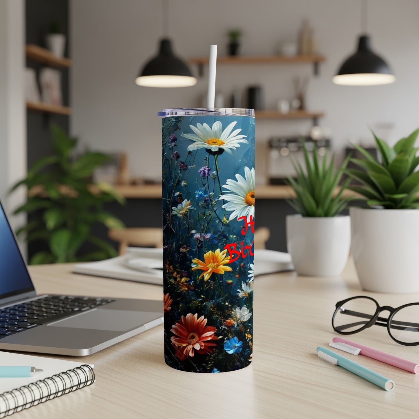 Tall tumbler with daisies and red "Happy Birthday" text on desk.