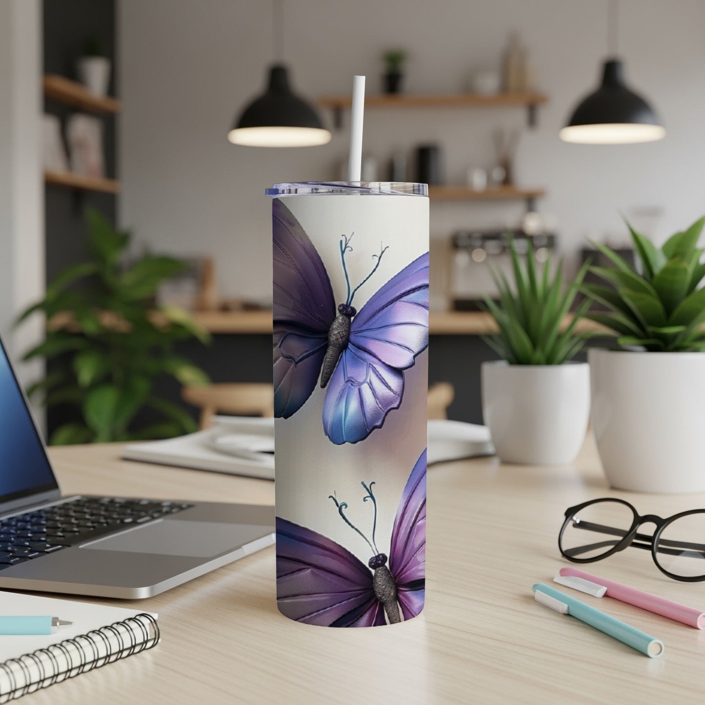 Tall tumbler with purple butterflies on a desk with a laptop.