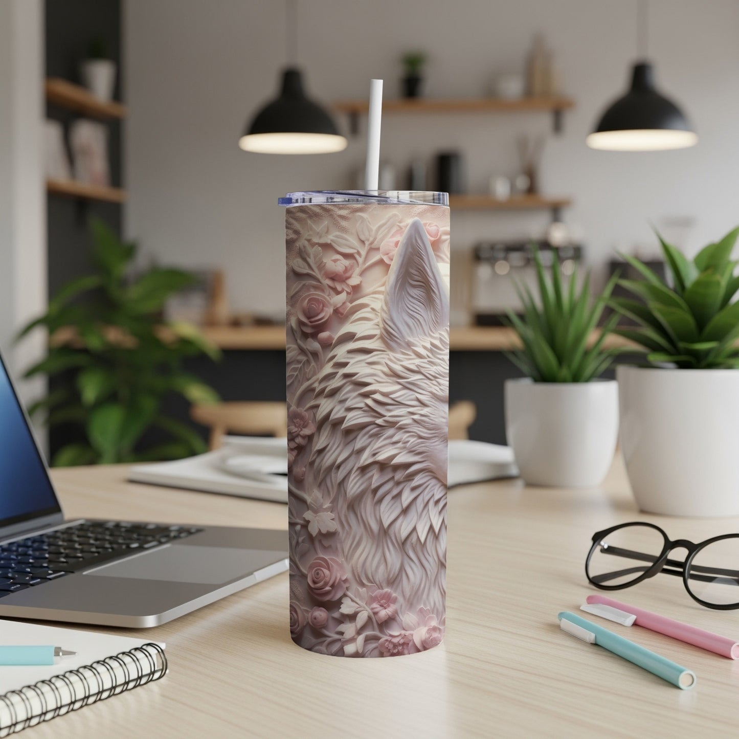 White wolf design tumbler with floral embossing on a desk.