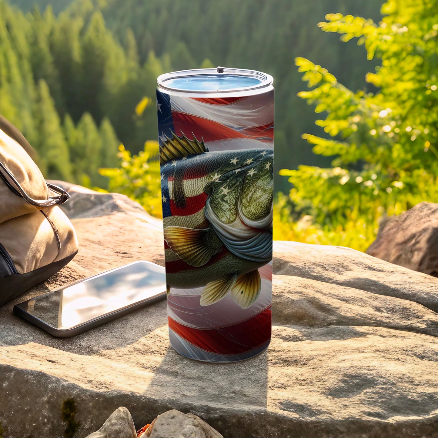 Bass fishing tumbler with American flag design, on rocks outdoors.