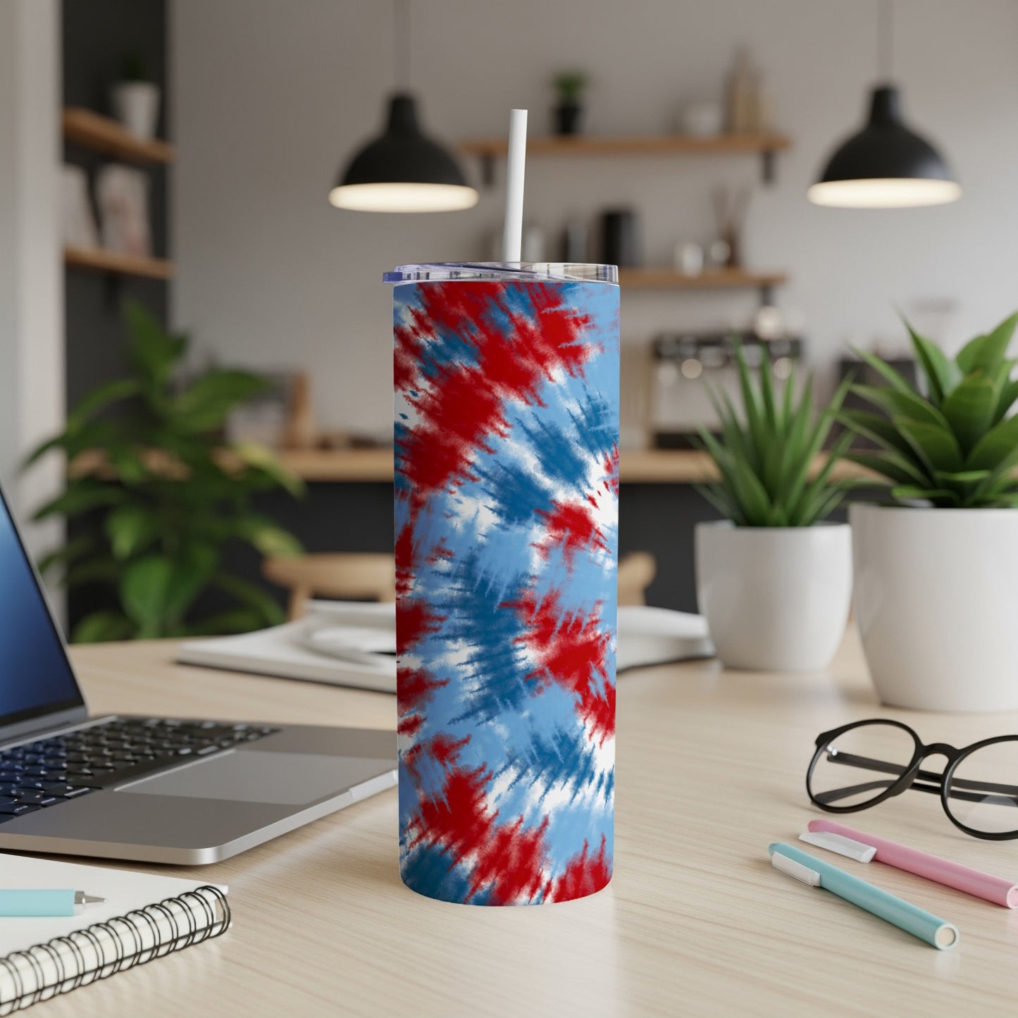 Tall insulated tumbler with red, white, and blue tie-dye pattern and a straw.