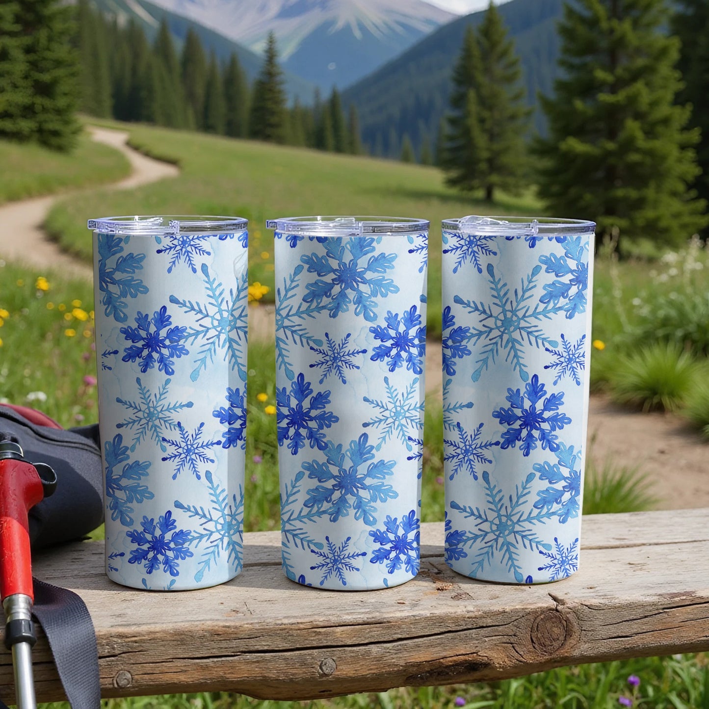 Three blue snowflake patterned tumblers on a wooden bench.
