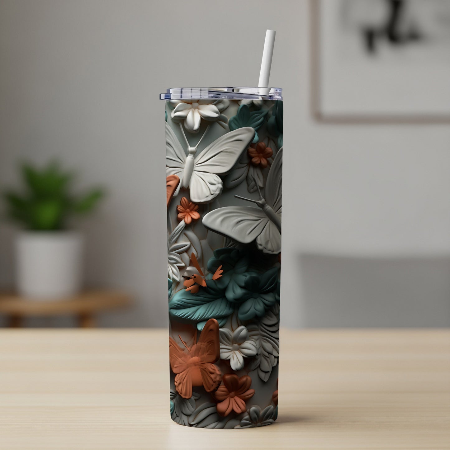 White and orange butterfly and floral relief on a tall, cylindrical tumbler with straw.