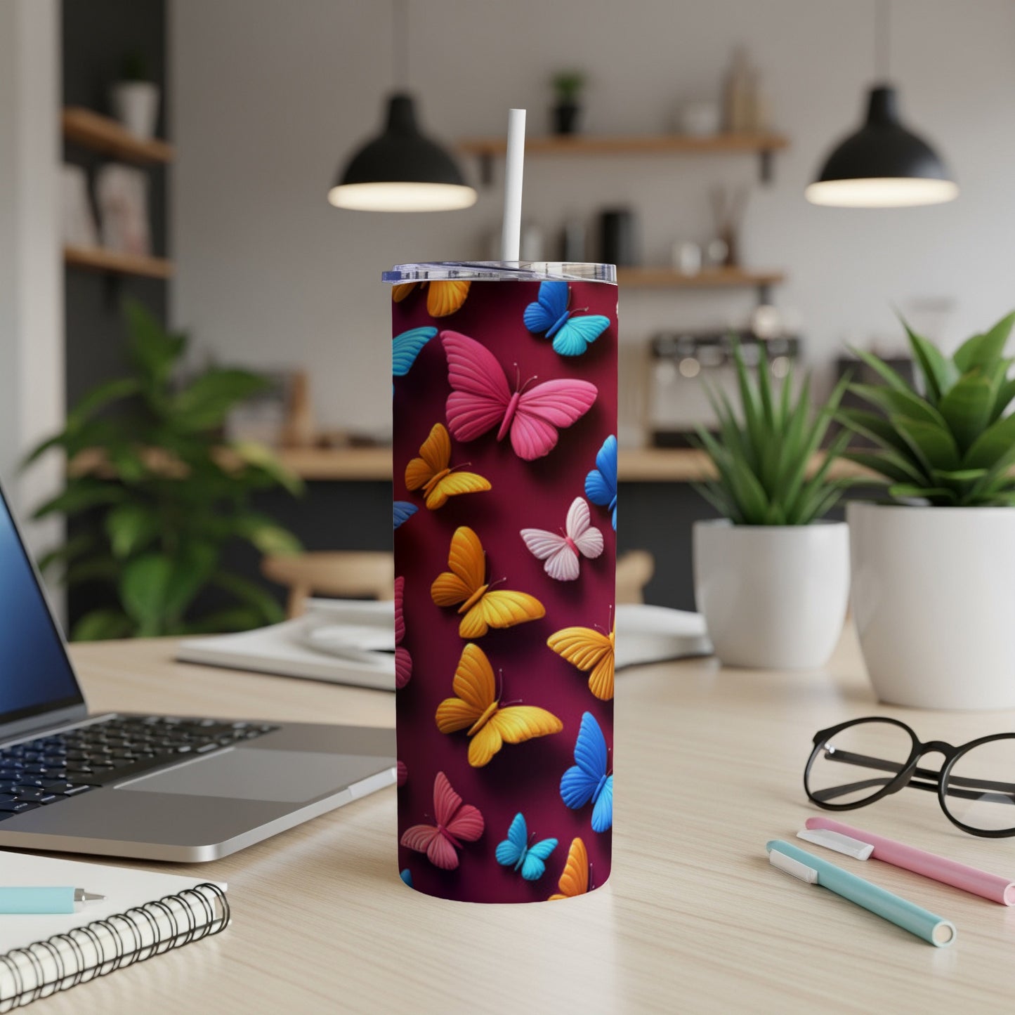 Red tumbler with colorful butterflies and a white straw on a desk.