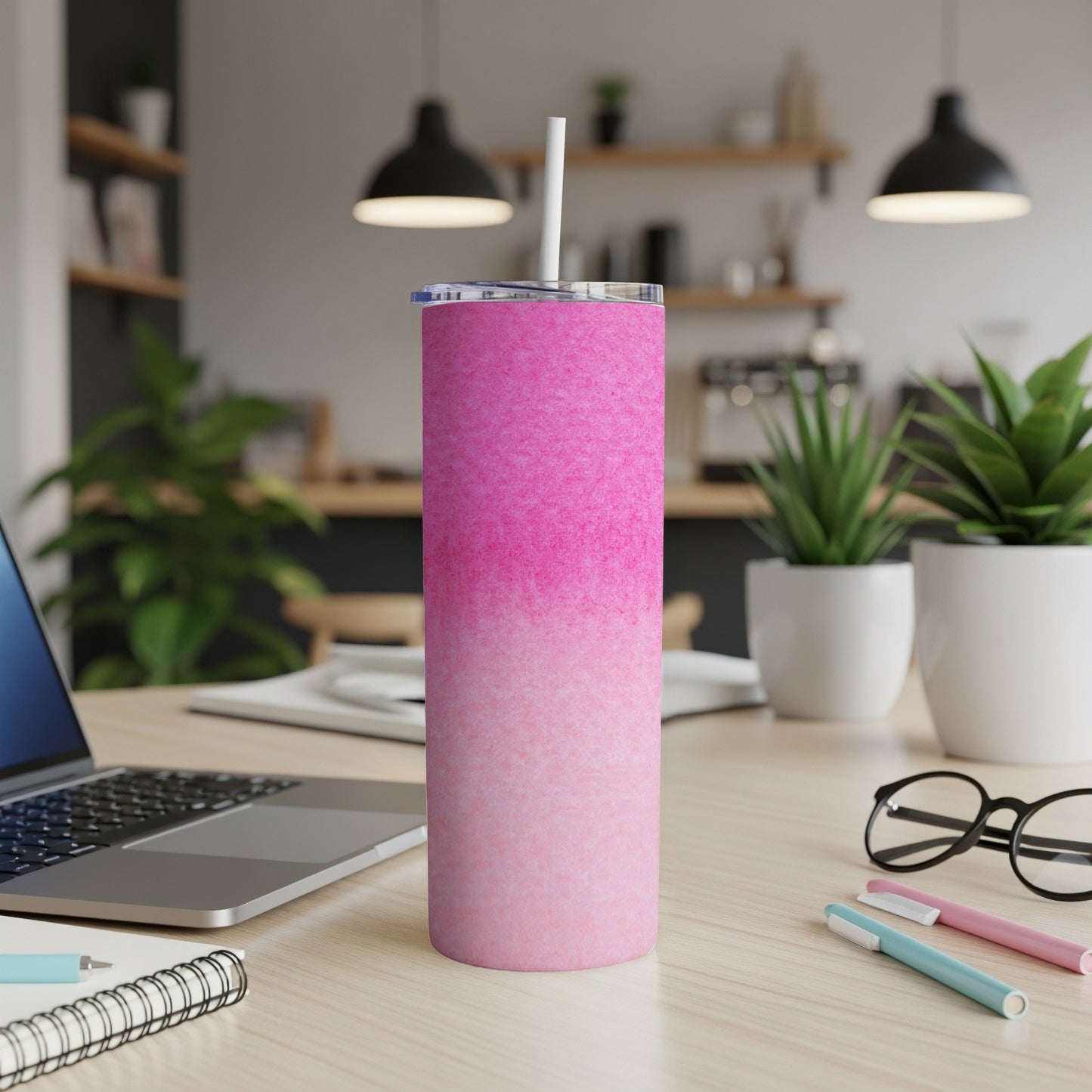 Pink gradient tumbler with white straw on a desk.