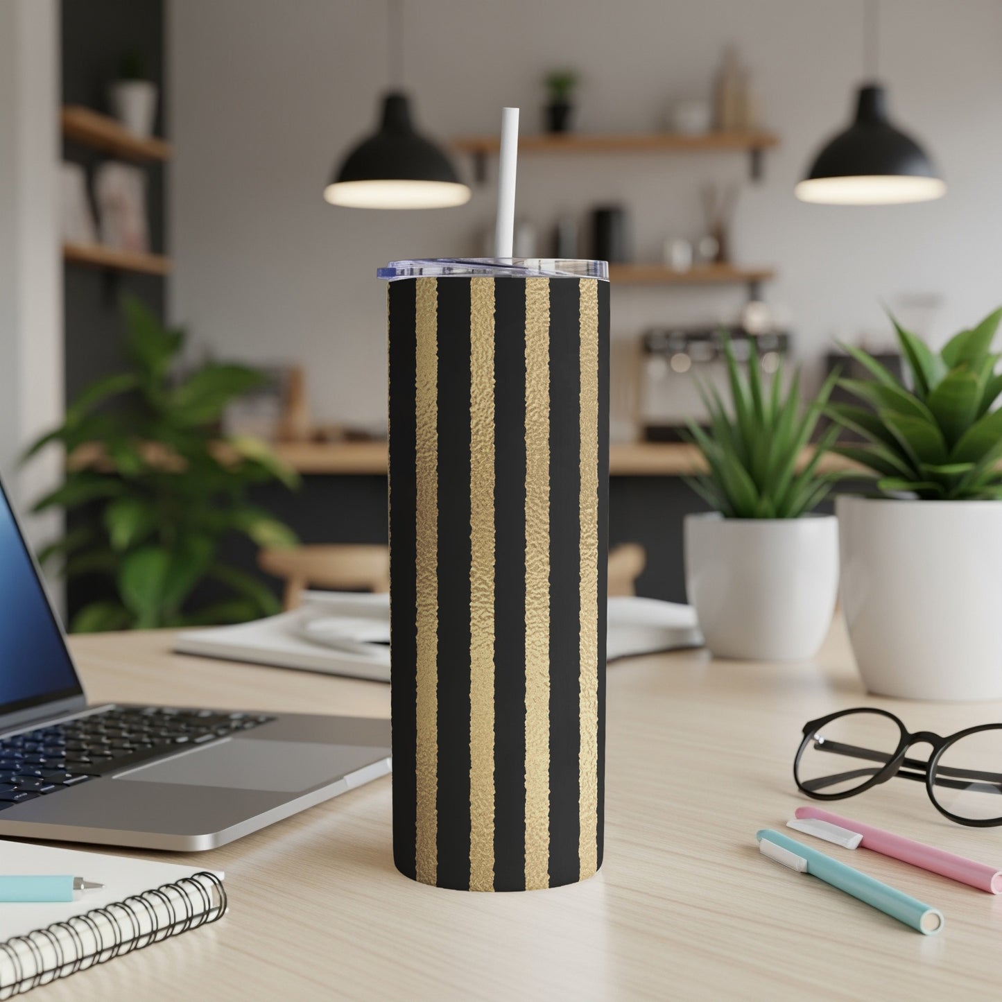 Black tumbler with gold vertical stripes and a white straw.