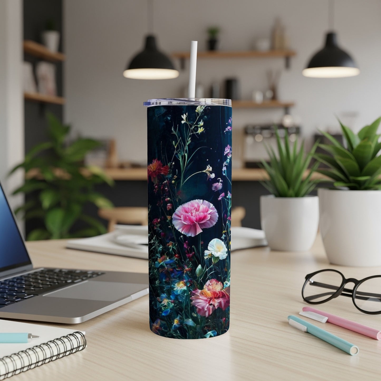 Floral patterned tumbler with straw on a wooden desk.