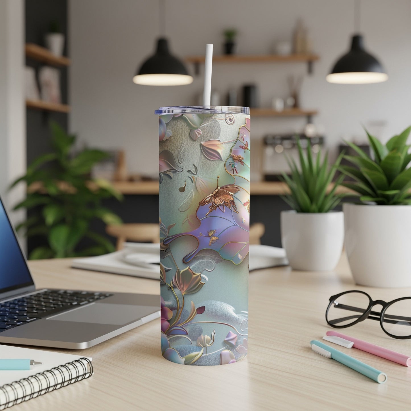 Iridescent tumbler with floral and butterfly design on a desk.