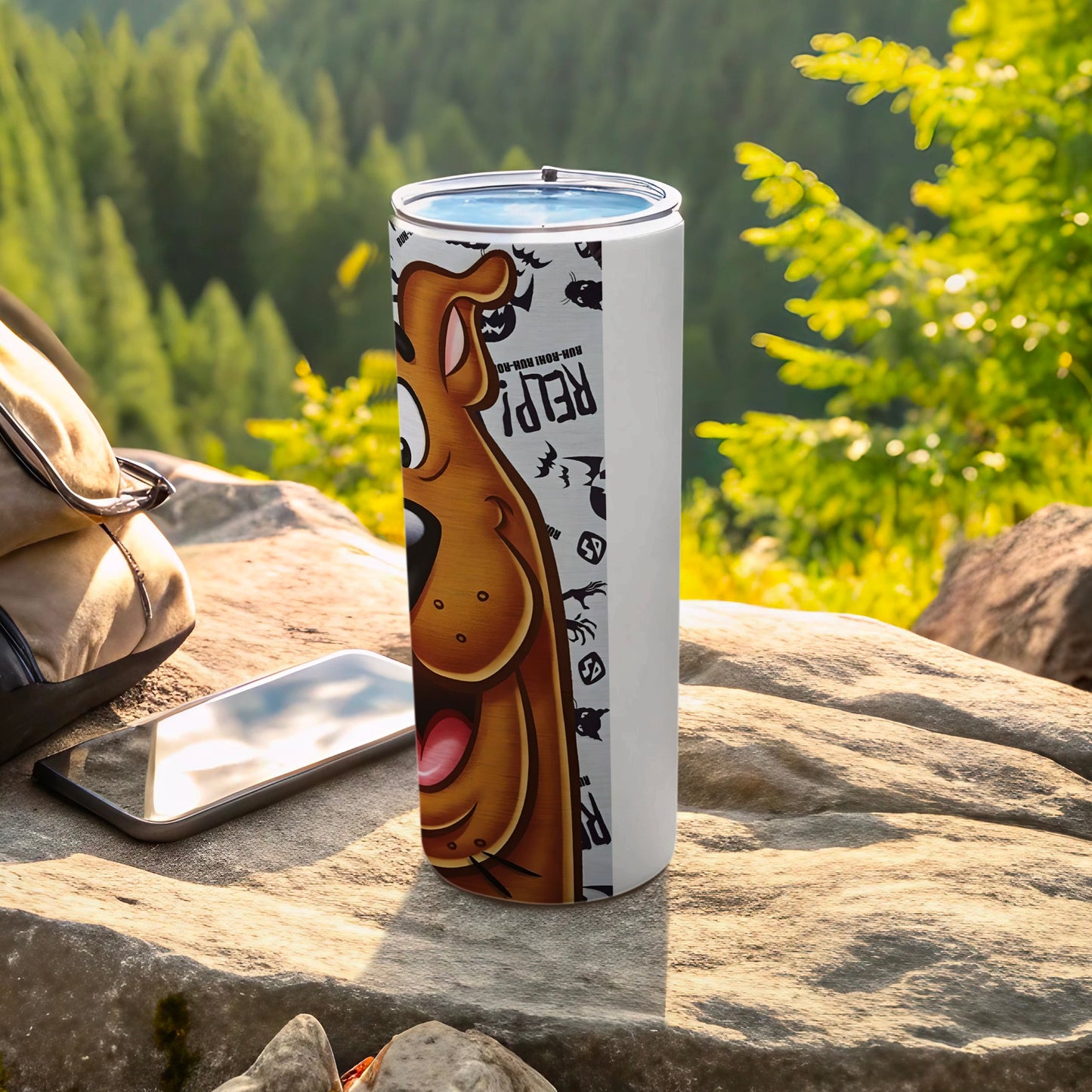 Scooby-Doo tumbler with a backpack and phone on rocks.
