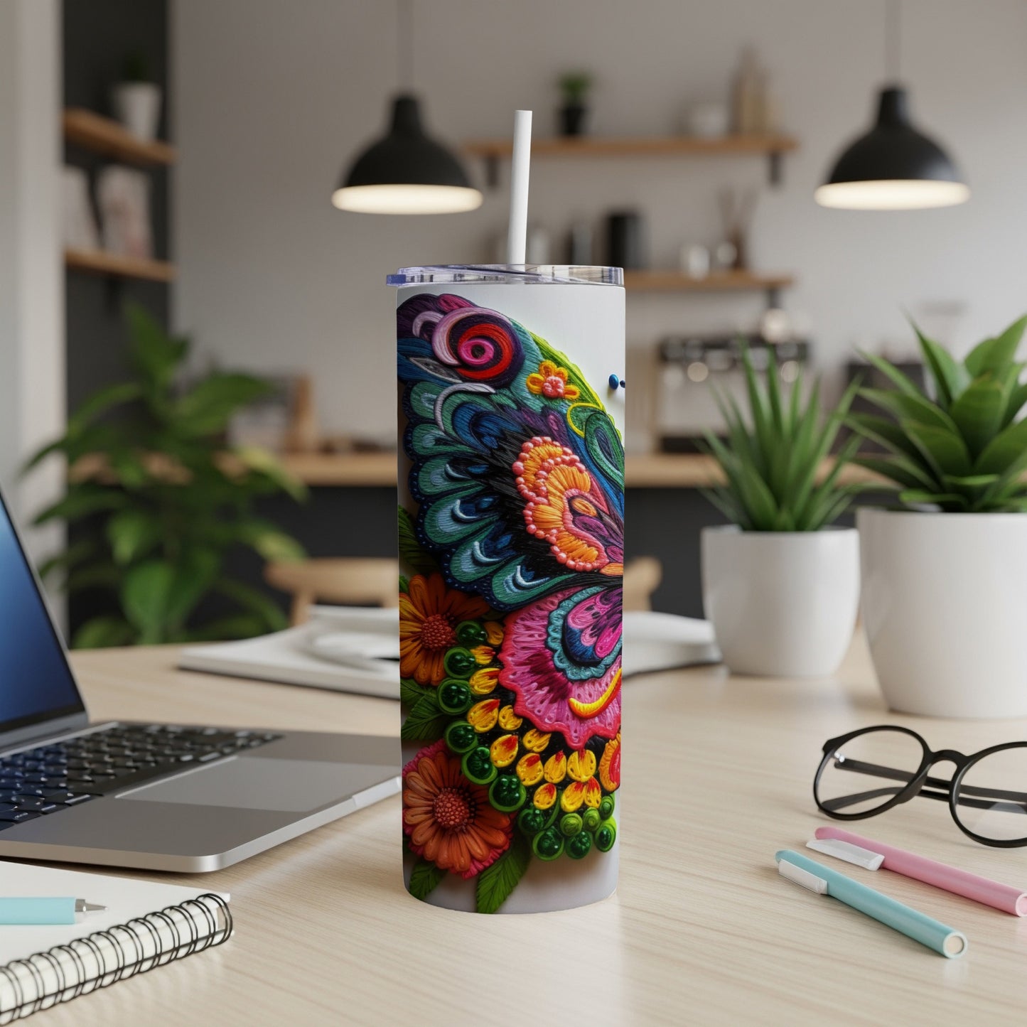 White tumbler with colorful butterfly design, straw, and office desk accessories.