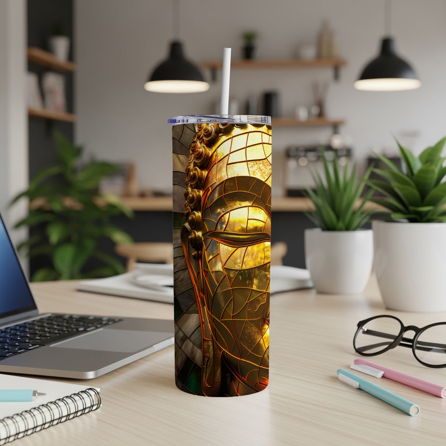 Gold stained glass Buddha head on a tumbler with a straw.