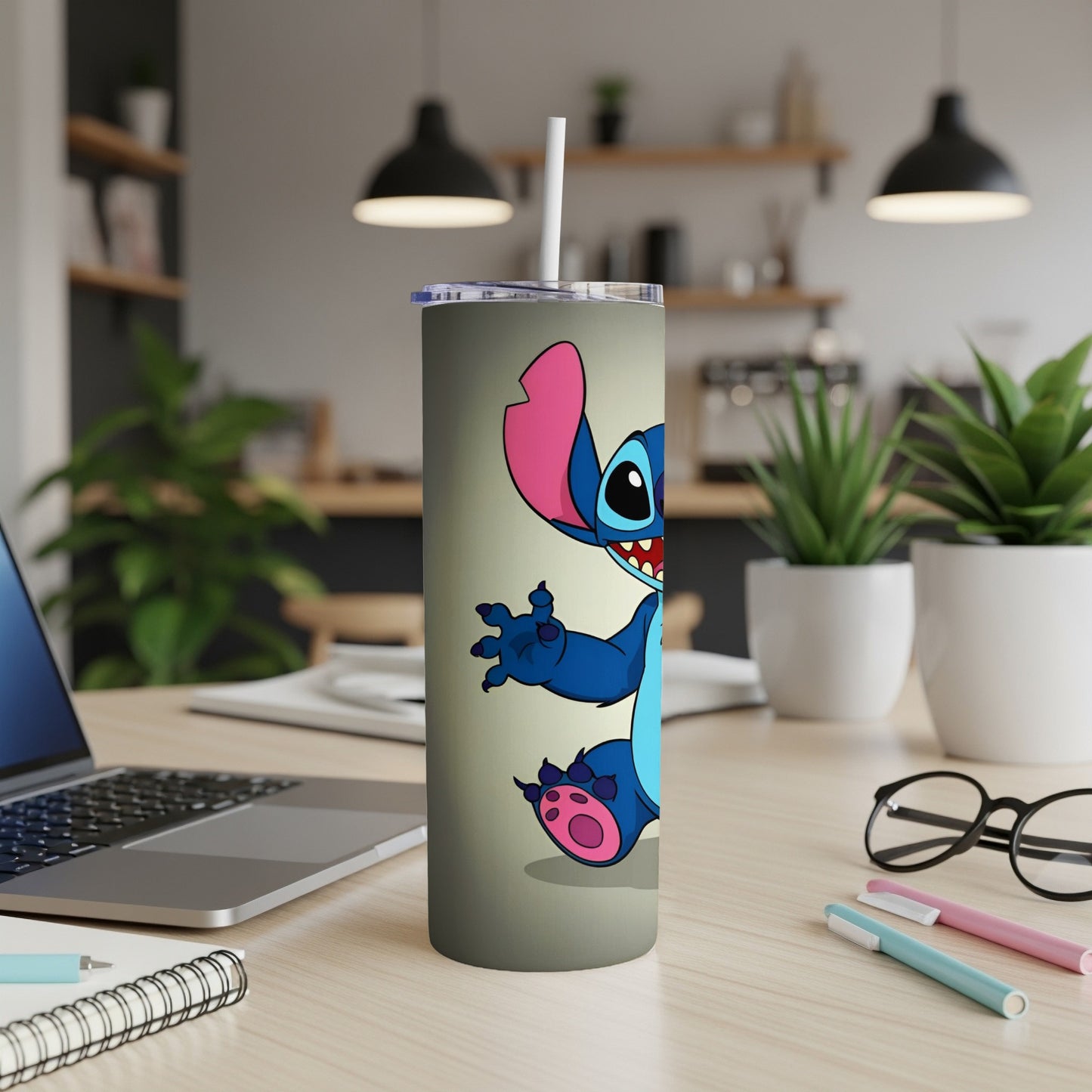 Stitch character on a gray tumbler with a straw on a desk.