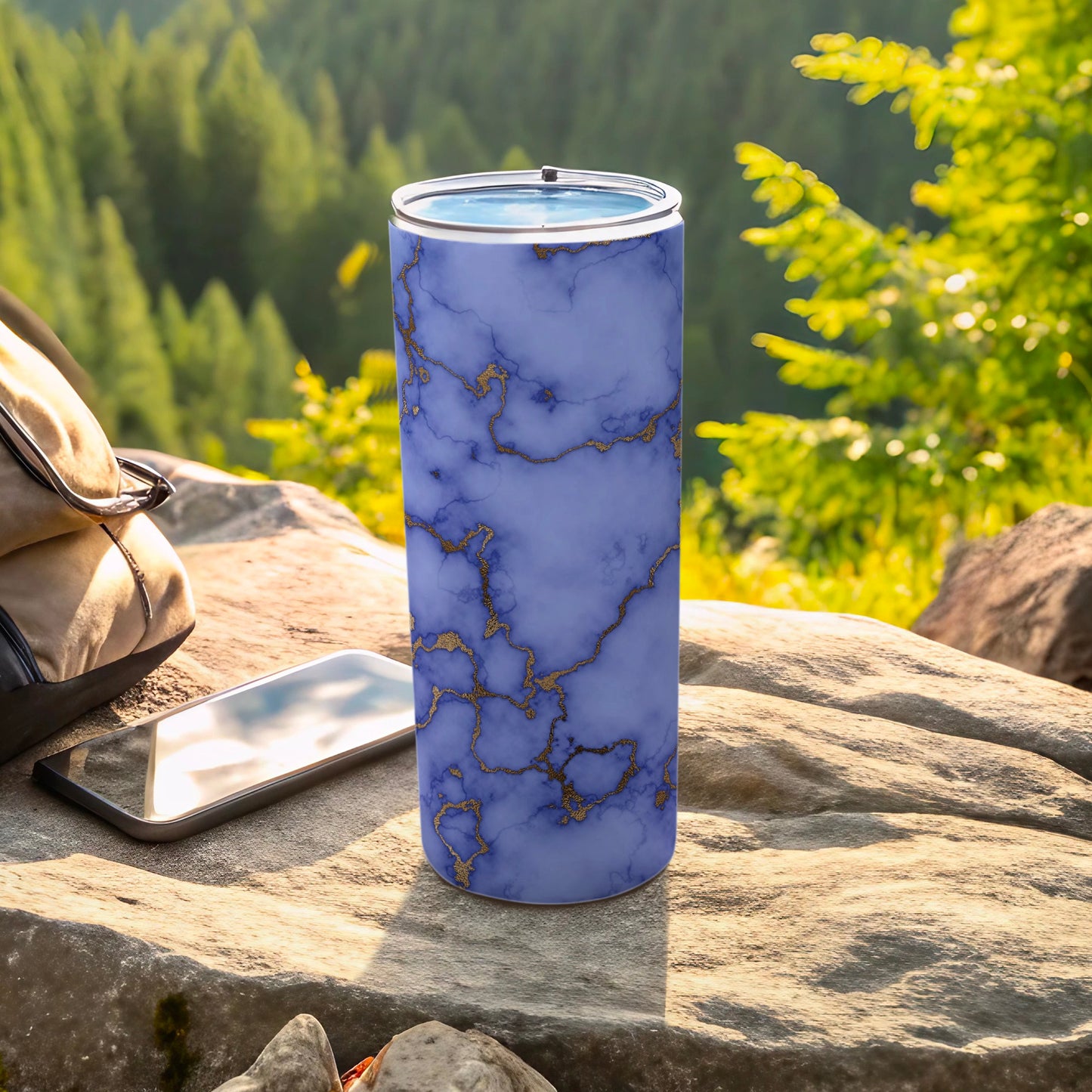 Purple marble tumbler with gold veins, on a rocky surface next to a phone.