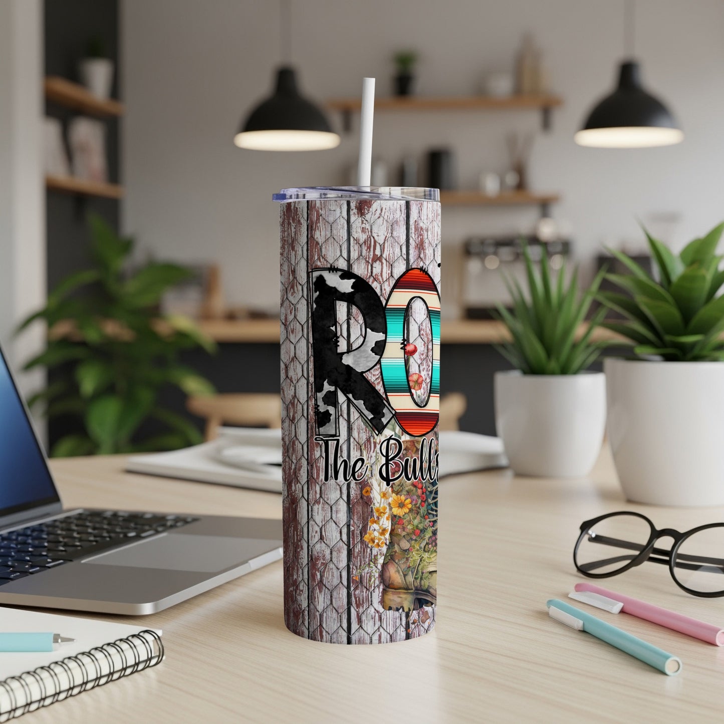 Wooden textured tumbler with "RO The Bull" and floral design on desk.