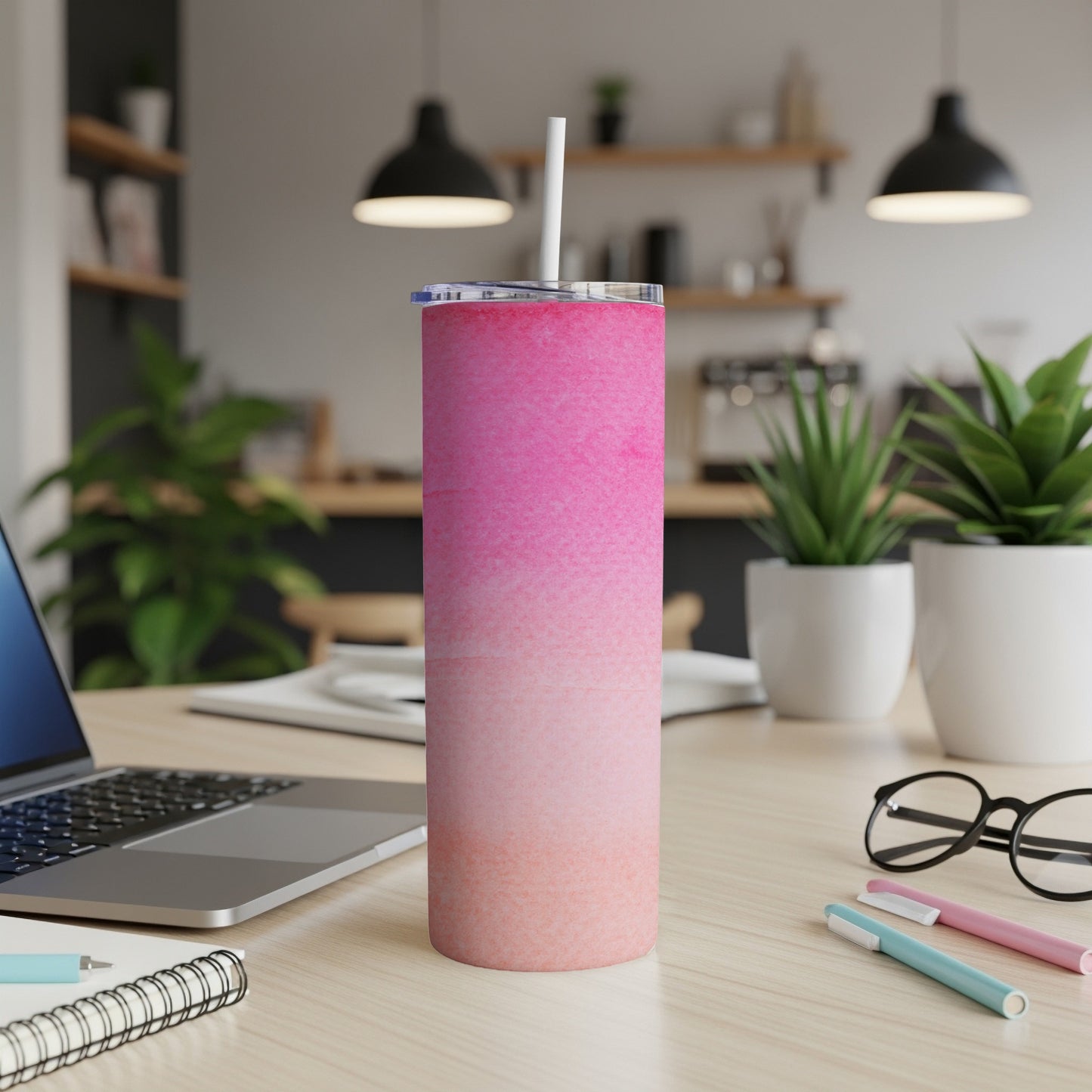 Pink gradient skinny tumbler with straw on a desk.