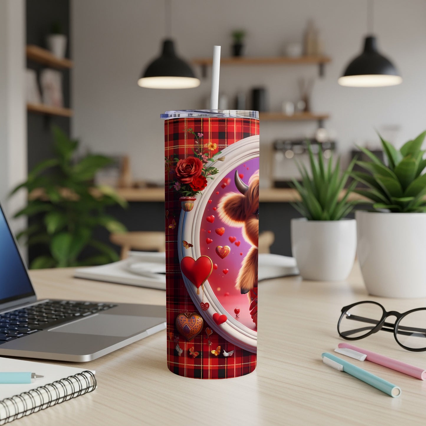 Red plaid tumbler with highland cow and hearts on a desk.