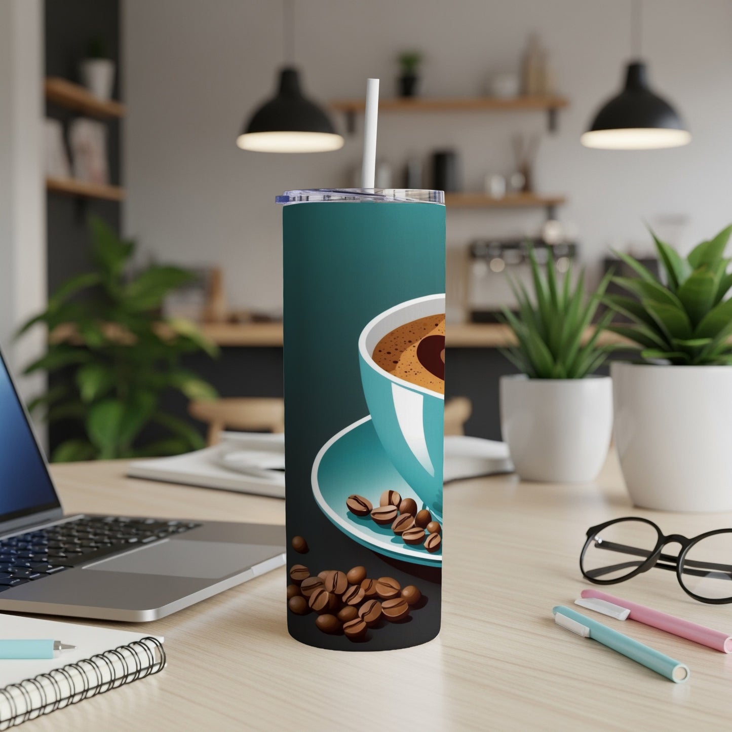 Teal coffee tumbler with coffee beans and a straw on a desk.