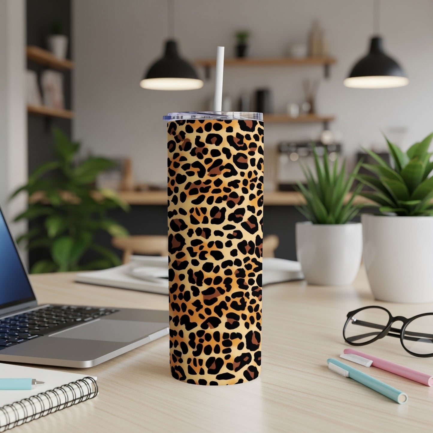 Leopard print tumbler with straw on a desk next to a laptop.