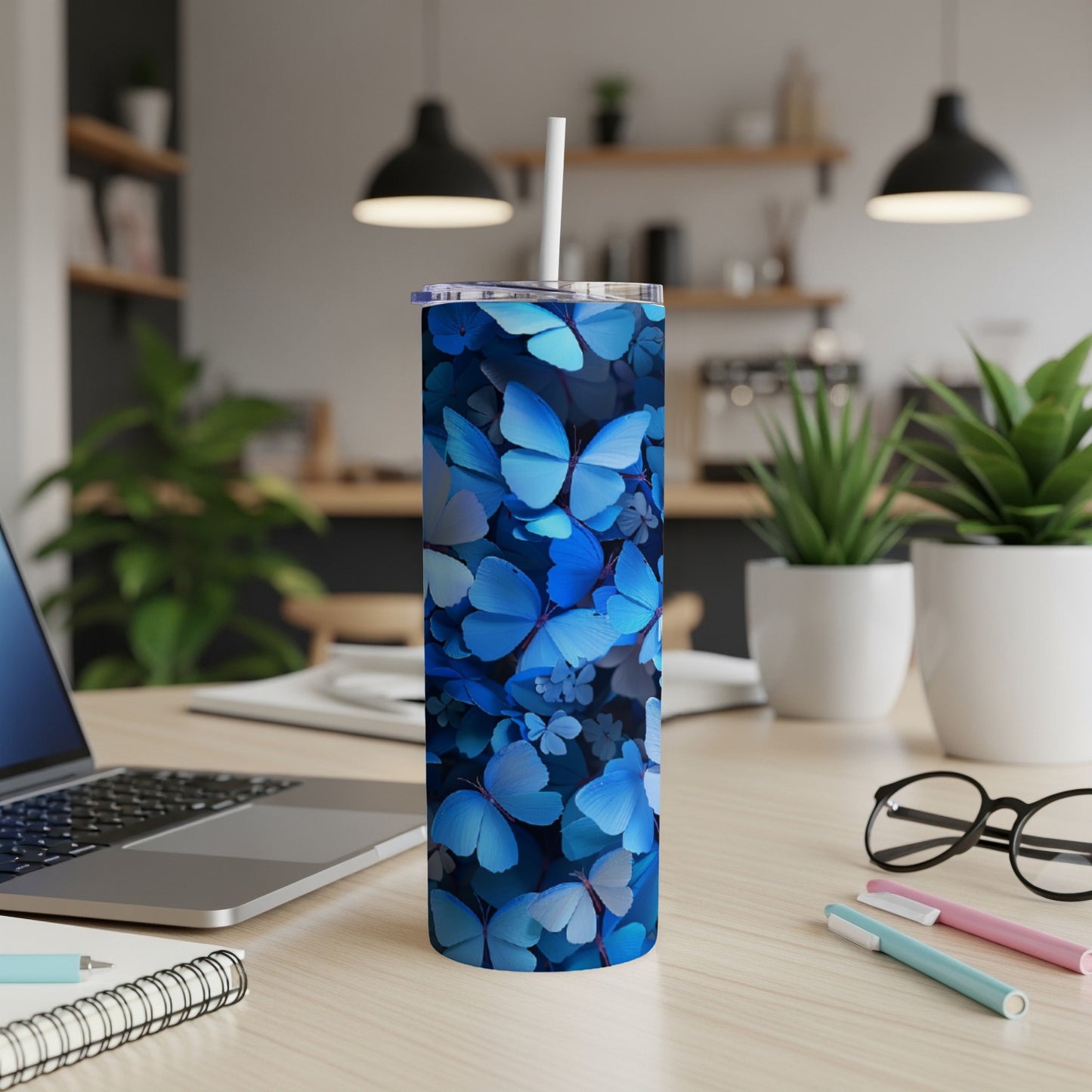 Blue butterfly patterned tumbler with a white straw on a desk.