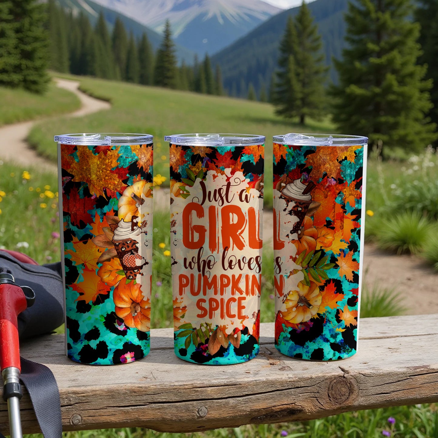 Three tumblers with pumpkin spice and leopard print designs sit on a wooden surface.