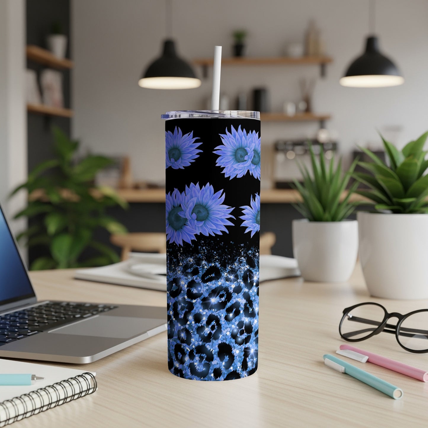 Blue floral leopard print skinny tumbler with straw on desk.
